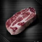 Iberico Schweinenackensteak aus Spanien mit feiner Marmorierung und kräftiger Fleischfarbe, roh im Anschnitt