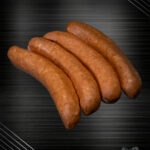 Käsekrainer aus Österreich im Rohzustand mit sichtbaren Käsewürfeln