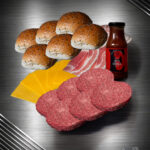 Burger Bundle mit Färse-Patties, Bacon, Buns, Käse, Pfeffer und Sauce auf dunklem Untergrund arrangiert