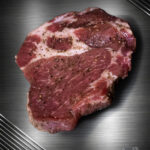 Schweinenackensteak mariniert vom regionalen Duroc Schwein mit sichtbarer Marmorierung und Kräutern im Rohzustand.