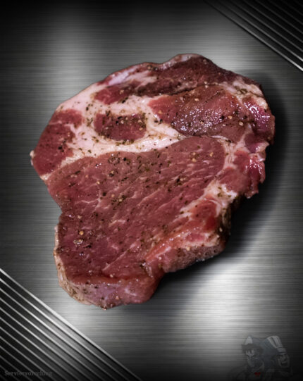 Schweinenackensteak mariniert vom regionalen Duroc Schwein mit sichtbarer Marmorierung und Kräutern im Rohzustand.