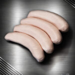 Saftige Berliner Currywurst mit Darm aus regionalem Schweinefleisch auf dunklem, edlem Untergrund