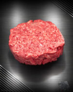 Rohes Haché Schweine-Burger Pattie aus grob gehacktem Schweinefleisch mit sichtbarer Struktur auf neutralem Untergrund.