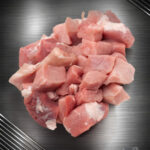 Rohes, gleichmäßig gewürfeltes Gulasch vom regionalen Strohschwein aus Schulter und Nacken auf hellem Untergrund