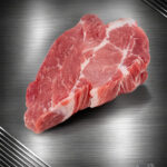 Rohes Nackensteak vom regionalen Strohschwein mit sichtbarer Marmorierung auf neutralem Hintergrund